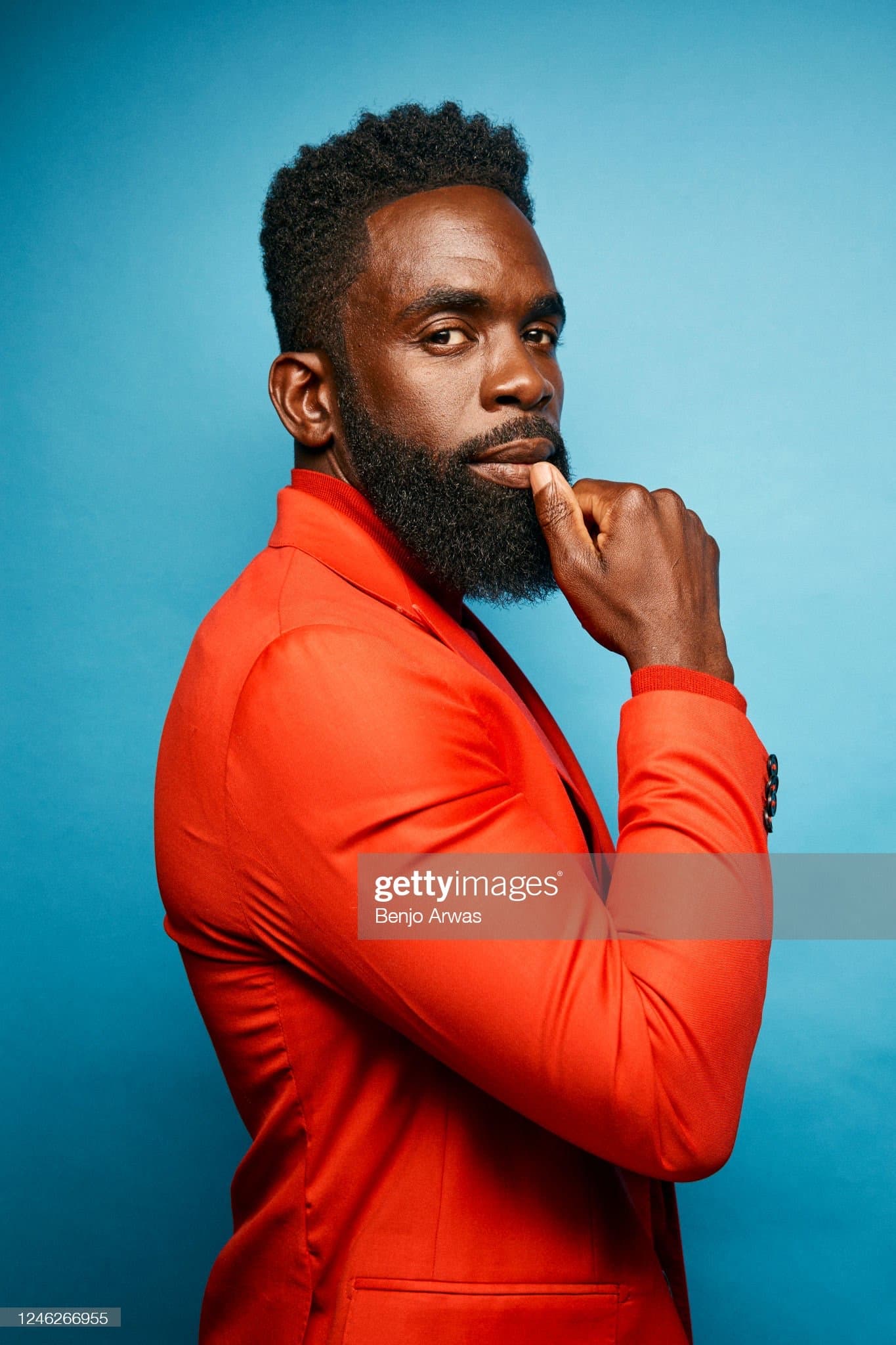 Scarlet single breasted blazer with a ribbed collar and cuffs, photographed in side profile against a blue studio backdrop.