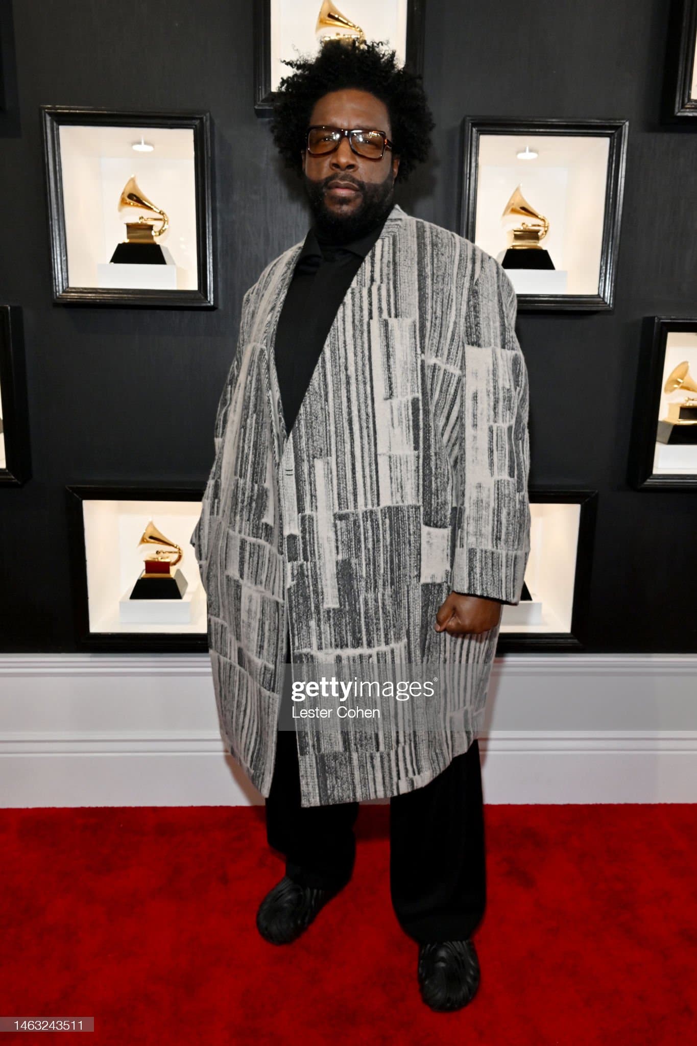 A guest at an awards ceremony in an oversized silver-printed coat over black.